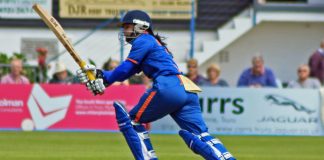 A female cricketer runs for the ball wearing a blue cricket strip