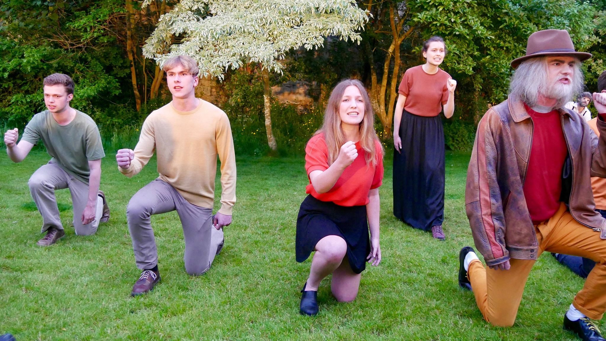 Five people kneeling in colourful clothes