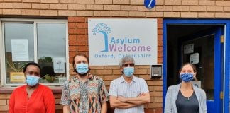 Four adults wearing masks in front of Asylum Welcome. From left to right: Caritas Umulisa, Simon Dawson, Almas Farzi ('Navid'), Helena Cullen
