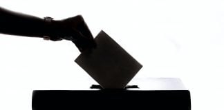 Silhouette of an arm putting an envelope into a box.