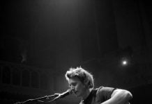 Ben Howard performing at Paradiso, Amsterdam, singing and playing the acoustic guitar whilst seated.