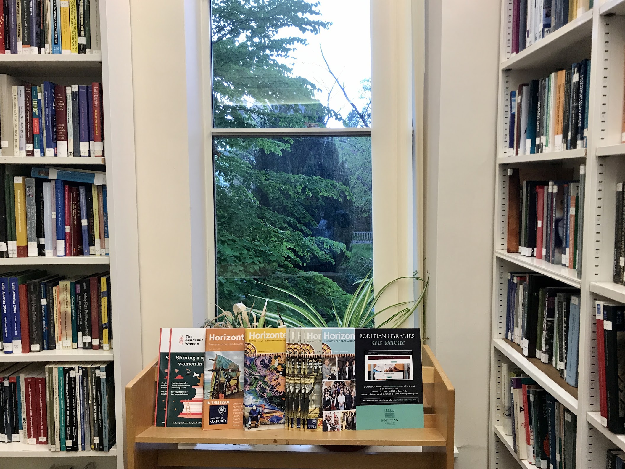 A photo taken inside of the Latin American Centre Library, showing bookshelves and a shelf of magazines. 