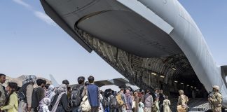 U.S. Airmen and U.S. Marines guide qualified evacuees aboard a U.S. Air Force C-17