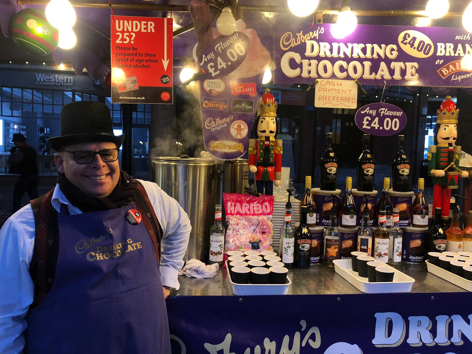Cadburys Chocolate stall, with a man in purple apron and black top hat.