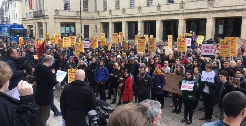 People holding yellow placards in front of the Clarendon building