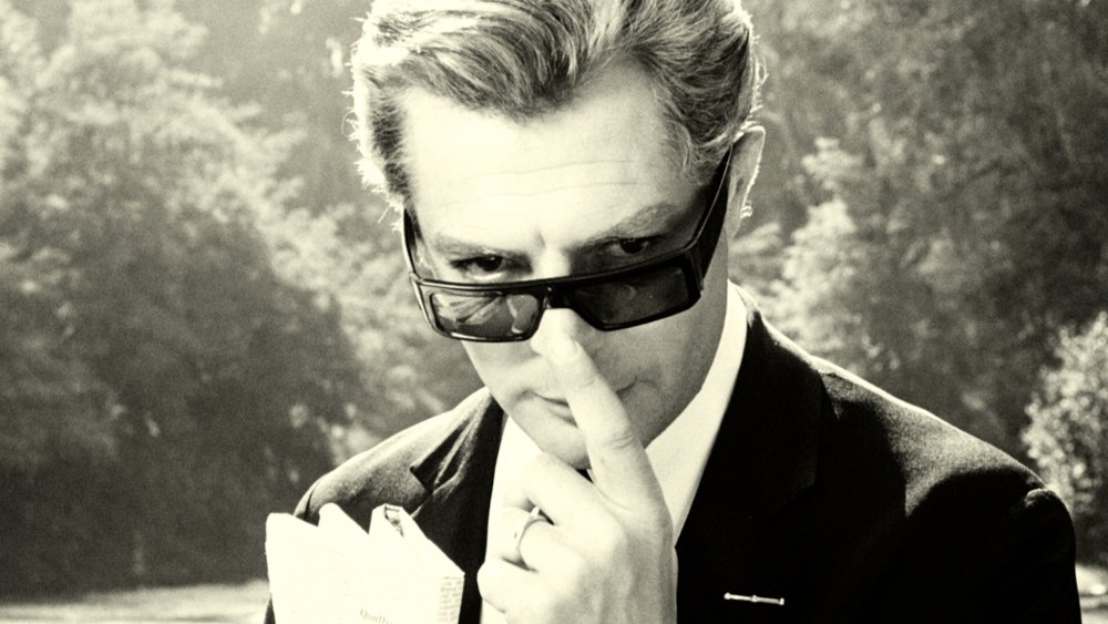 Close-up of Marcello Mastroianni as Guido, pushing up his sunglasses