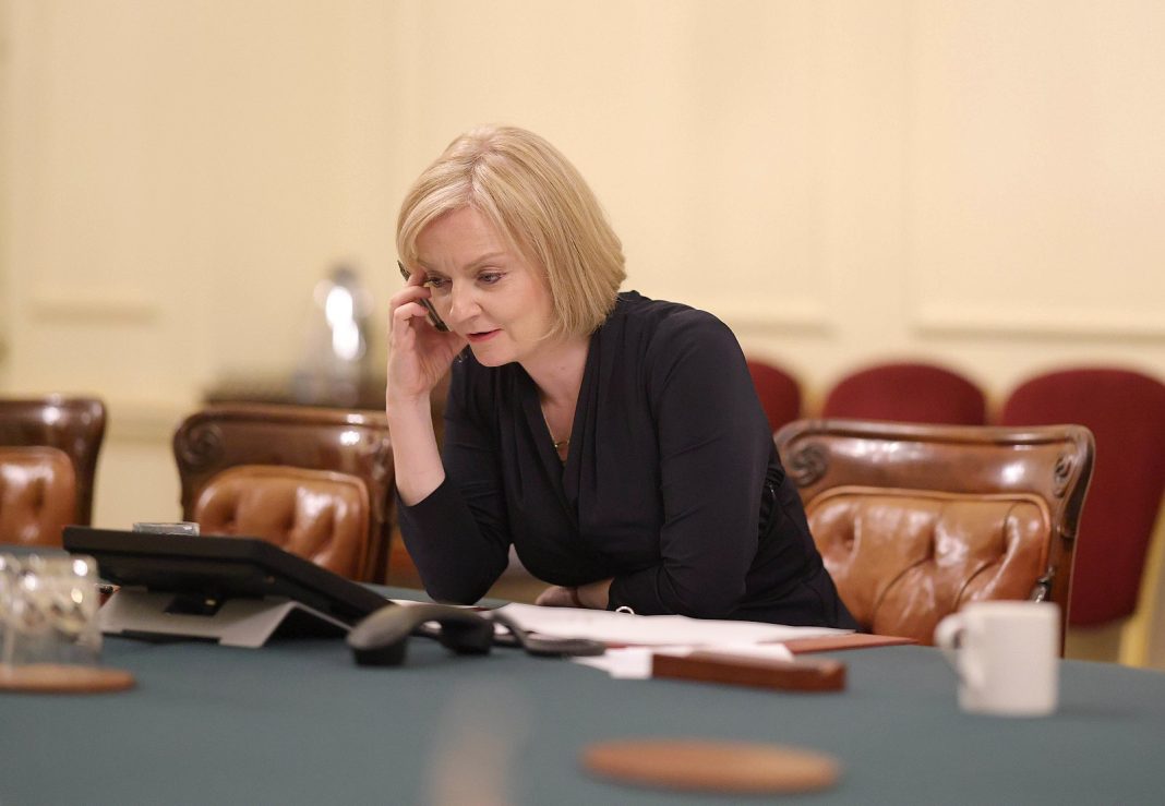 Ex-Prime Minister Liz Truss sits with her head in her hands at Downing Street.