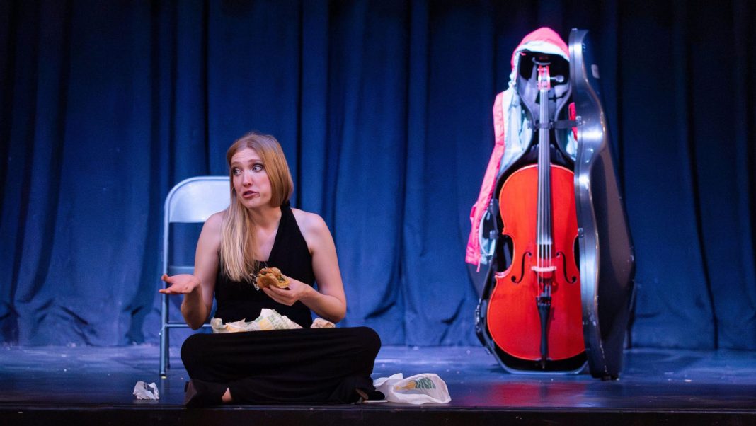 Karen Hall sitting beside her cello on stage