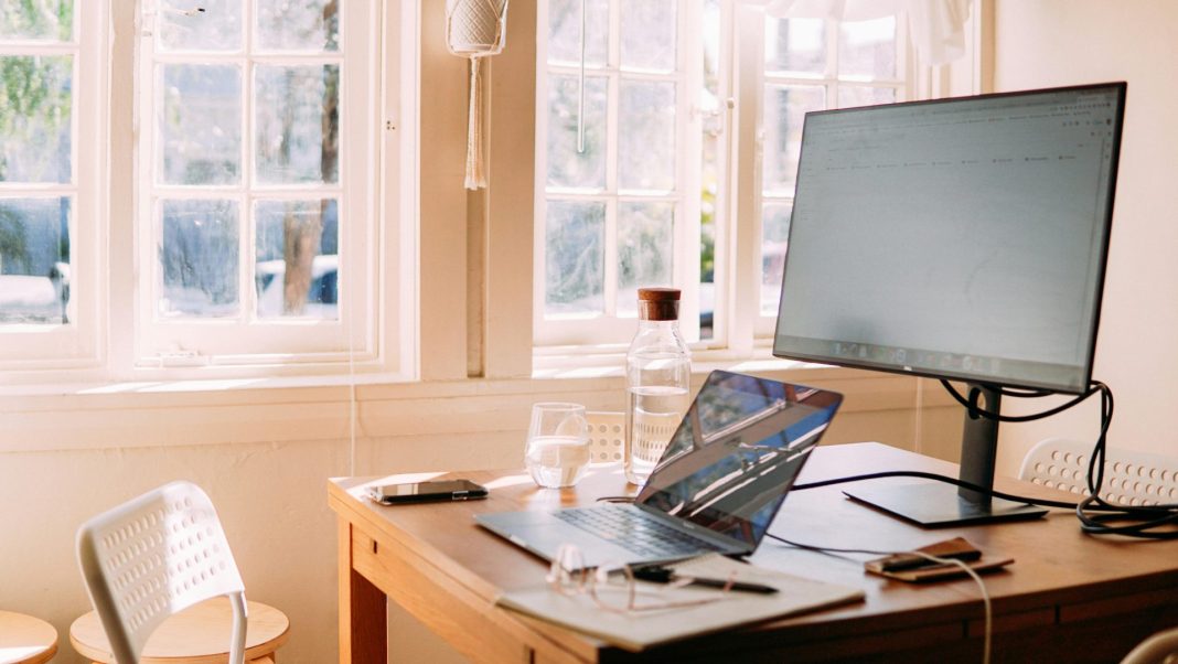 Laptop and monitor by a window.